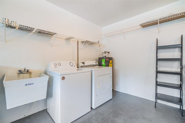 laundry room with sink, washing machine and dryer, a textured ceiling, and electric water heater