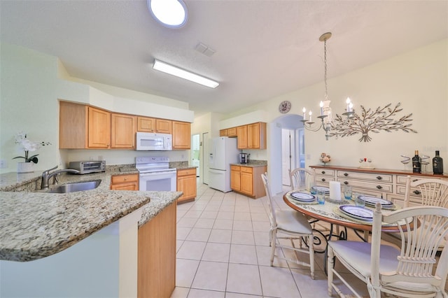 kitchen with light stone counters, light tile patterned floors, sink, a notable chandelier, and white appliances