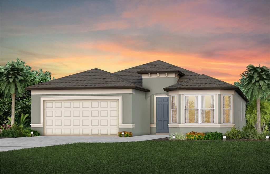 view of front facade with a garage, a shingled roof, driveway, stucco siding, and a front yard