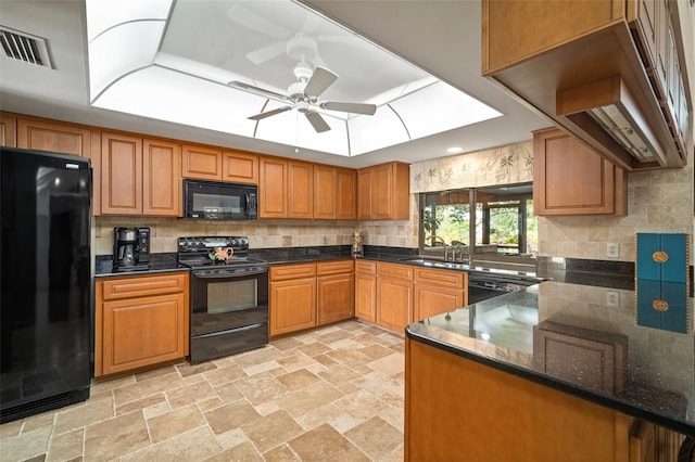 kitchen with dark stone counters, black appliances, sink, ceiling fan, and kitchen peninsula