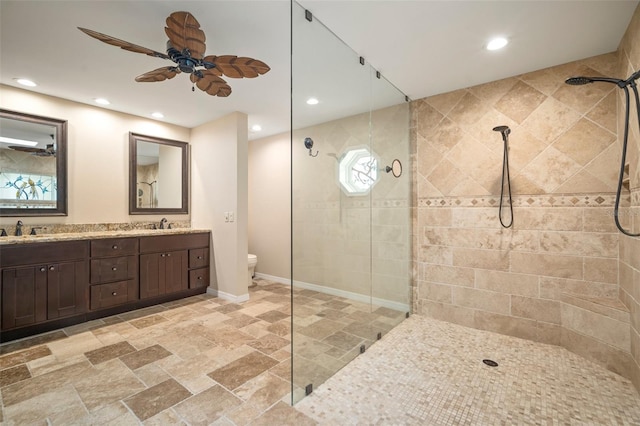 bathroom with vanity, ceiling fan, toilet, and tiled shower