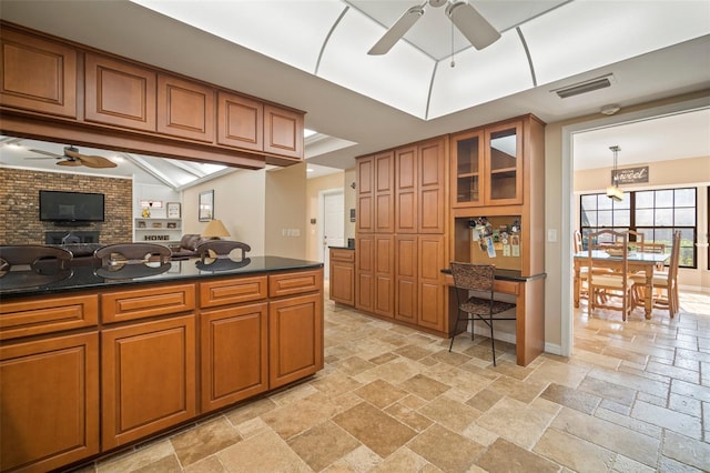 kitchen with a fireplace, hanging light fixtures, and ceiling fan