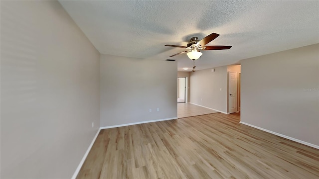 spare room featuring visible vents, light wood-style floors, a ceiling fan, a textured ceiling, and baseboards