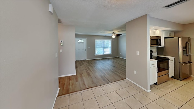 kitchen featuring stainless steel appliances, visible vents, white cabinetry, open floor plan, and light countertops