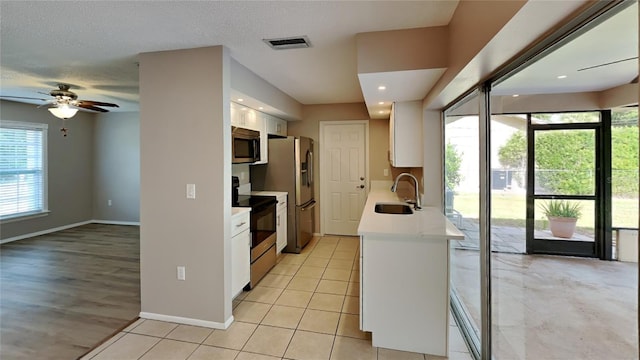 kitchen with white cabinets, appliances with stainless steel finishes, light countertops, and a sink