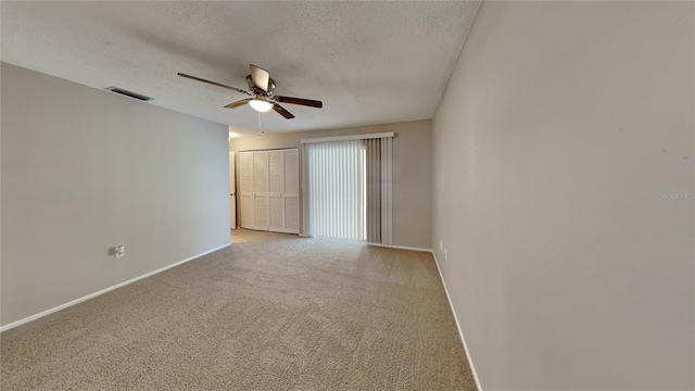 empty room with visible vents, baseboards, light colored carpet, ceiling fan, and a textured ceiling