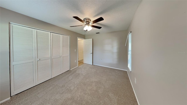 unfurnished bedroom with a textured ceiling, light carpet, a ceiling fan, baseboards, and a closet