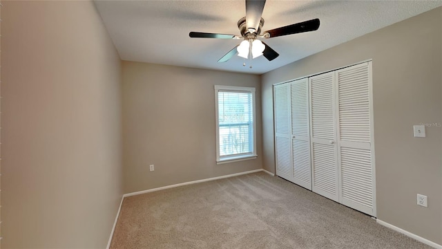 unfurnished bedroom featuring ceiling fan, a textured ceiling, light carpet, baseboards, and a closet