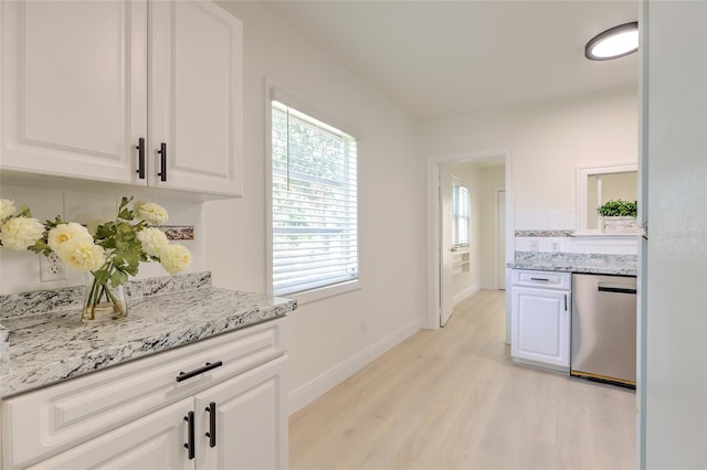 kitchen with light wood-type flooring, stainless steel dishwasher, and white cabinetry