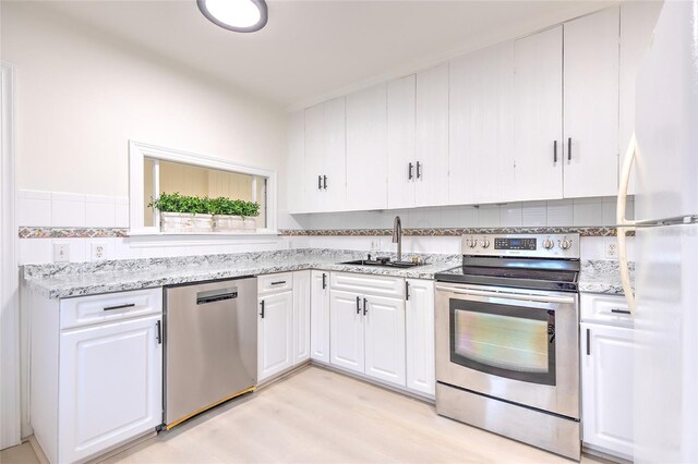 kitchen featuring white cabinets, light hardwood / wood-style floors, light stone countertops, sink, and stainless steel appliances