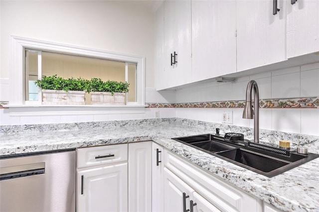 kitchen with backsplash, sink, light stone counters, stainless steel dishwasher, and white cabinetry