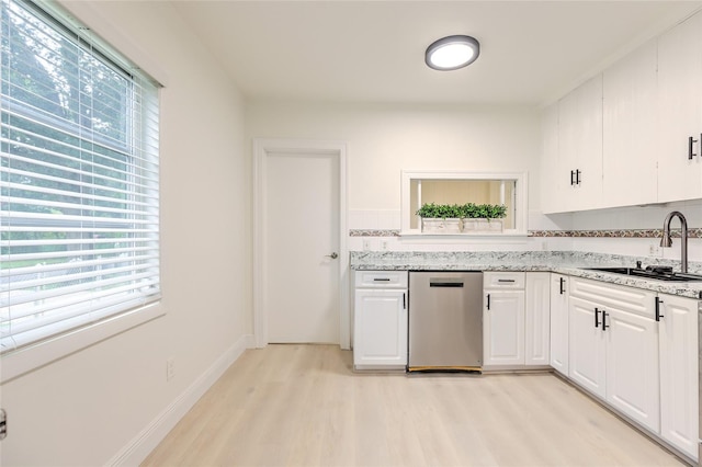 kitchen with a wealth of natural light, light wood-type flooring, stainless steel dishwasher, and sink