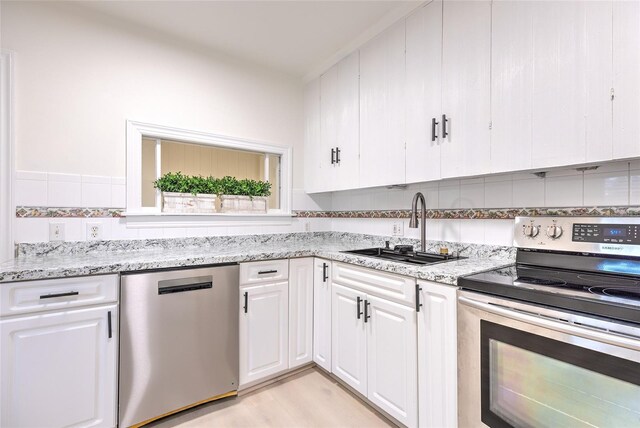 kitchen featuring light hardwood / wood-style flooring, tasteful backsplash, white cabinetry, sink, and stainless steel appliances