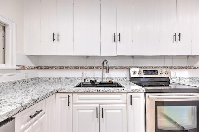 kitchen featuring tasteful backsplash, stainless steel electric range, white cabinetry, light stone counters, and sink