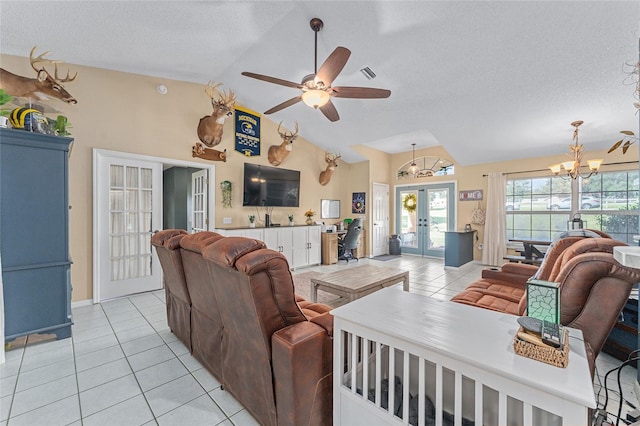 tiled living room with ceiling fan with notable chandelier, french doors, a textured ceiling, and high vaulted ceiling