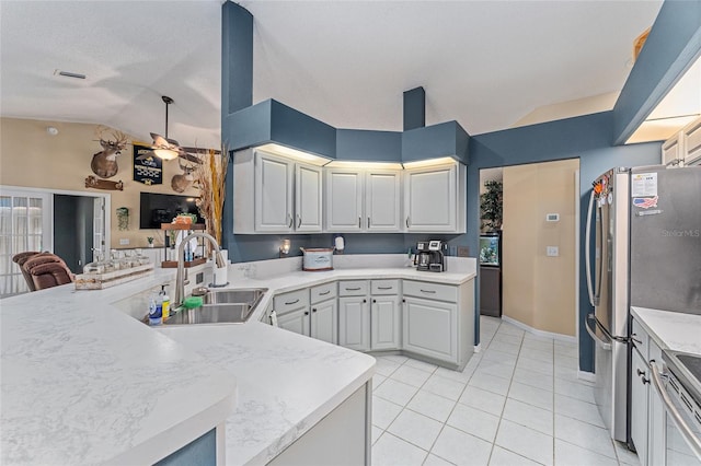 kitchen featuring vaulted ceiling, light tile patterned floors, kitchen peninsula, sink, and stainless steel appliances