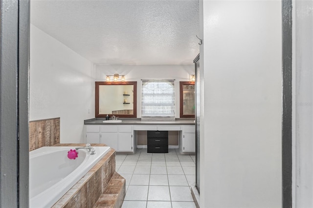 bathroom featuring vanity, a textured ceiling, a relaxing tiled tub, and tile patterned flooring