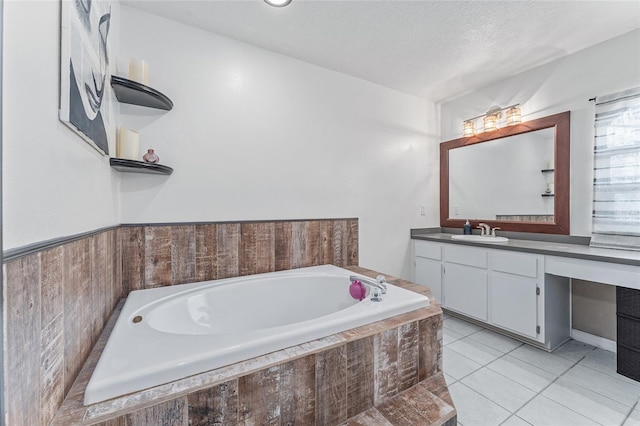 bathroom featuring a textured ceiling, tiled bath, vanity, and tile patterned flooring