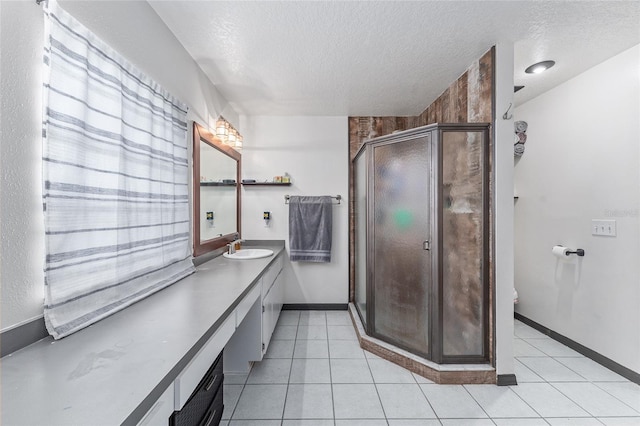 bathroom featuring a shower with shower door, tile patterned flooring, a textured ceiling, and vanity