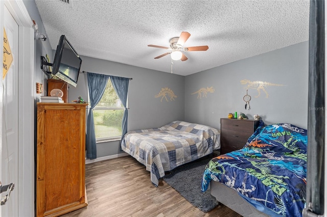 bedroom with a textured ceiling, ceiling fan, and hardwood / wood-style floors