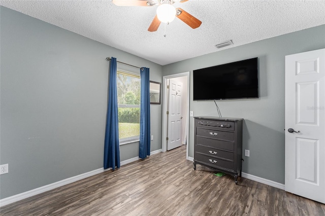 bedroom with hardwood / wood-style floors, ceiling fan, and a textured ceiling