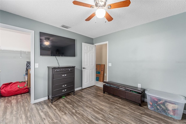 interior space with a textured ceiling, hardwood / wood-style floors, ceiling fan, and a closet