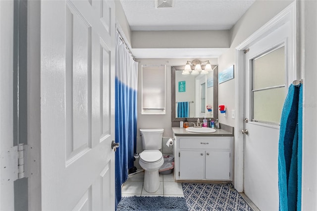 bathroom with vanity, toilet, tile patterned floors, and a textured ceiling