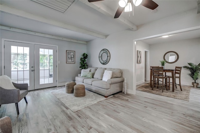 living room featuring ceiling fan, light wood-type flooring, beamed ceiling, and french doors