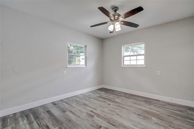 spare room featuring a wealth of natural light, ceiling fan, and hardwood / wood-style flooring