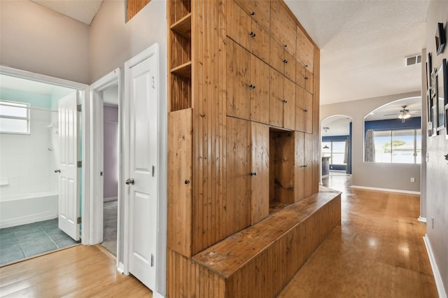 6843 Runner Oak Dr, Wesley Chapel, FL 33545 - hall with arched walkways, visible vents, a textured ceiling, and light wood-style flooring