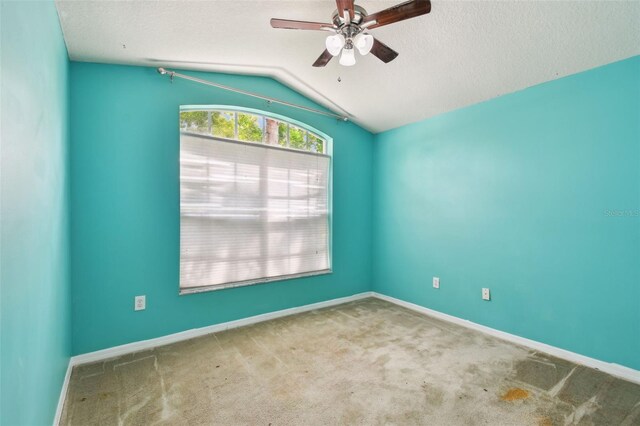 carpeted empty room with ceiling fan, a textured ceiling, and lofted ceiling