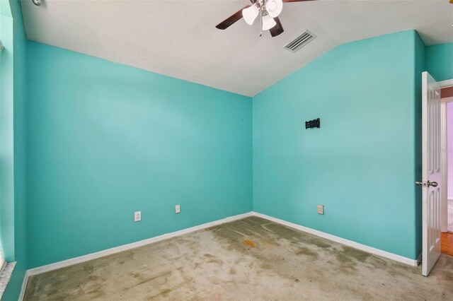 spare room featuring ceiling fan, vaulted ceiling, carpet, and a textured ceiling