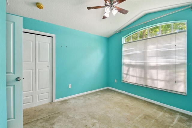 unfurnished room featuring ceiling fan, light colored carpet, and lofted ceiling