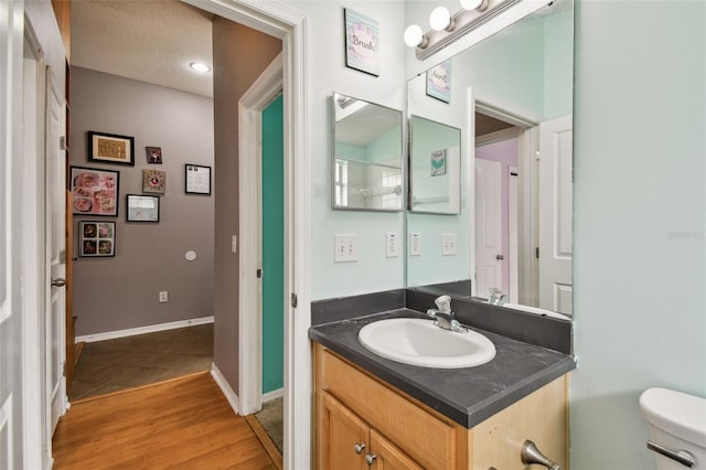 bathroom with hardwood / wood-style flooring, vanity, and toilet