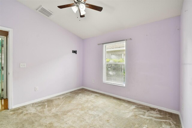 spare room featuring light colored carpet, vaulted ceiling, and ceiling fan