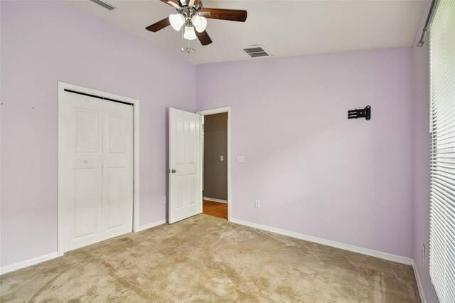 unfurnished bedroom with a closet, ceiling fan, light colored carpet, and lofted ceiling