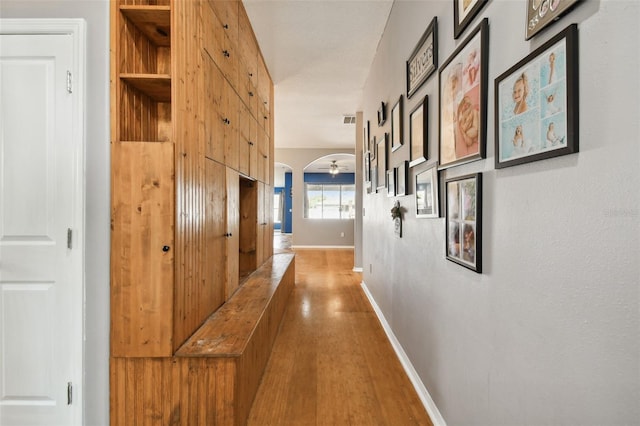 6843 Runner Oak Dr, Wesley Chapel, FL 33545 - hall featuring arched walkways, visible vents, baseboards, and wood finished floors
