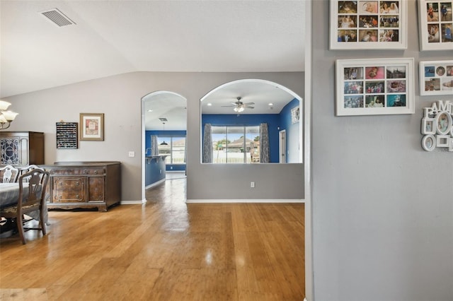 6843 Runner Oak Dr, Wesley Chapel, FL 33545 - hallway with baseboards, visible vents, arched walkways, wood finished floors, and vaulted ceiling