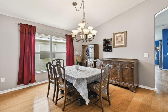 dining space featuring light hardwood / wood-style floors, vaulted ceiling, and a notable chandelier