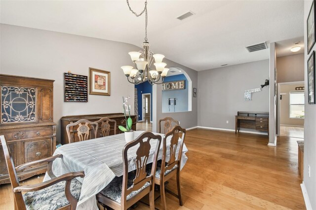 dining space featuring a notable chandelier, vaulted ceiling, and light hardwood / wood-style floors