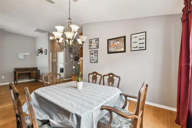 dining area featuring vaulted ceiling, hardwood / wood-style flooring, and a chandelier