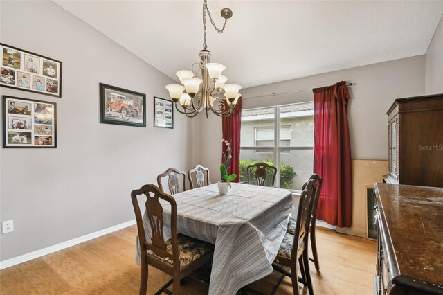 dining area with an inviting chandelier, light hardwood / wood-style floors, and lofted ceiling