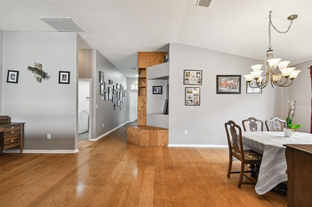 dining area featuring vaulted ceiling, wood-type flooring, and a chandelier