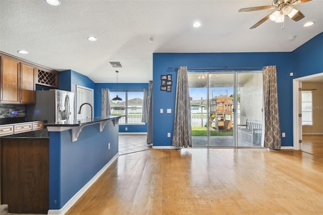 kitchen featuring decorative light fixtures, tasteful backsplash, light tile patterned floors, ceiling fan, and a breakfast bar