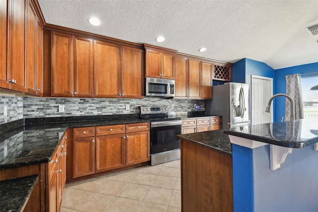 kitchen with a breakfast bar, sink, appliances with stainless steel finishes, tasteful backsplash, and light tile patterned floors