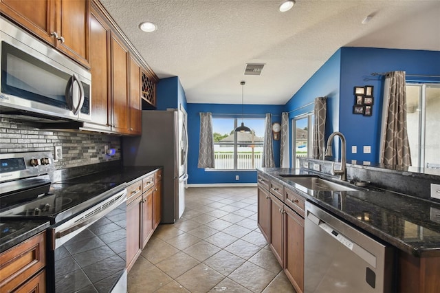6843 Runner Oak Dr, Wesley Chapel, FL 33545 - kitchen with decorative backsplash, dark stone counters, stainless steel appliances, pendant lighting, and a sink