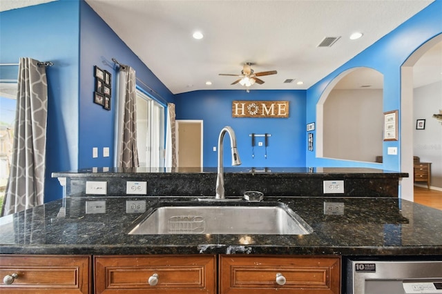 kitchen featuring dark stone counters, hardwood / wood-style floors, sink, and lofted ceiling