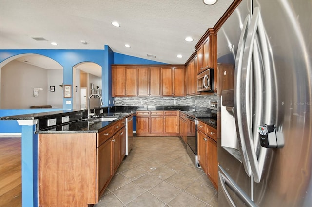 6843 Runner Oak Dr, Wesley Chapel, FL 33545 - kitchen with appliances with stainless steel finishes, vaulted ceiling, a sink, an island with sink, and dark stone counters