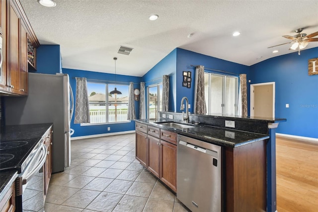 6843 Runner Oak Dr, Wesley Chapel, FL 33545 - kitchen with pendant lighting, stainless steel appliances, lofted ceiling, a sink, and dark stone countertops