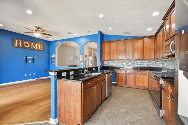 kitchen with appliances with stainless steel finishes, backsplash, light hardwood / wood-style floors, sink, and ceiling fan